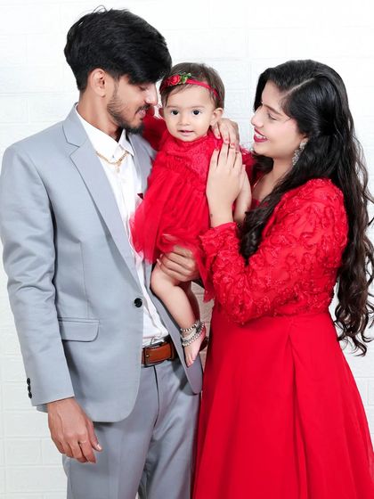 A sweet family photo with mom, dad, and their baby girl dressed in matching red. This portrait beautifully captures the love and unity of the family.