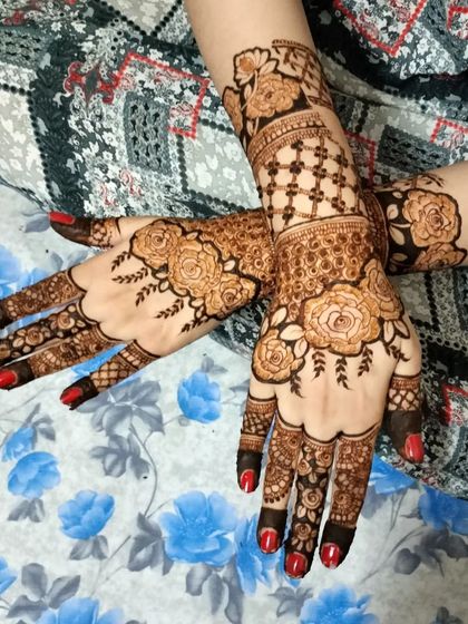 A very popular style combining hanging floral elements with grid patterns on the wrist. The bright red nails really make the fresh henna paste pop.
