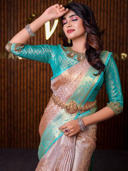 This model is wearing a unique beige and teal saree. The drape is styled to highlight the unusual color combination and the intricate blouse neckline.
