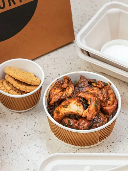 Our Andhra Gongura Chicken, a tangy and spicy delicacy, is packed to travel. We include our house-made biscuits on the side for a crunchy contrast to the tender chicken.