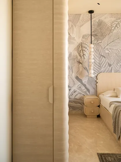 The guest bedroom in our 'Soft Serve' project blends minimalism with organic touches. A botanical mural serves as a backdrop to the custom curved wooden bed, creating the calming ambiance of a boutique bed and breakfast.