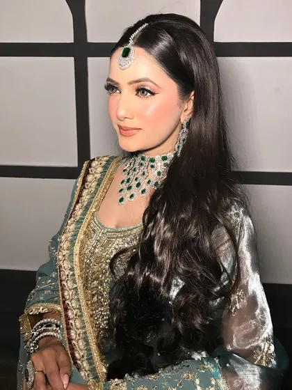 A full shot of the client in her Pakistani-inspired outfit, the emerald jewelry adding a beautiful contrast.