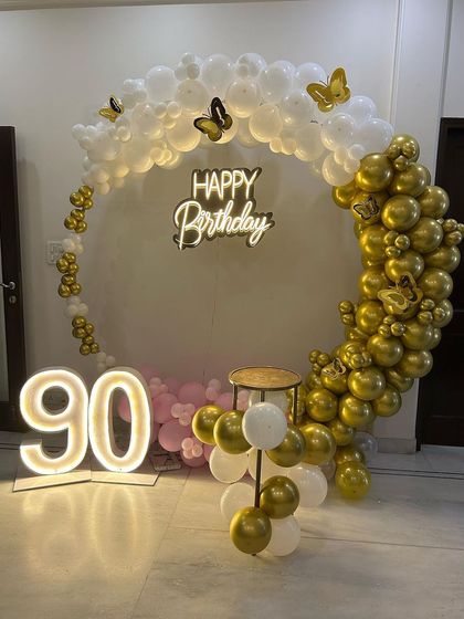 A beautiful and elegant 90th birthday celebration. The circular balloon arch in white and gold, adorned with delicate butterflies, created a graceful and celebratory backdrop. The large, illuminated '90' marked this incredible milestone in style.