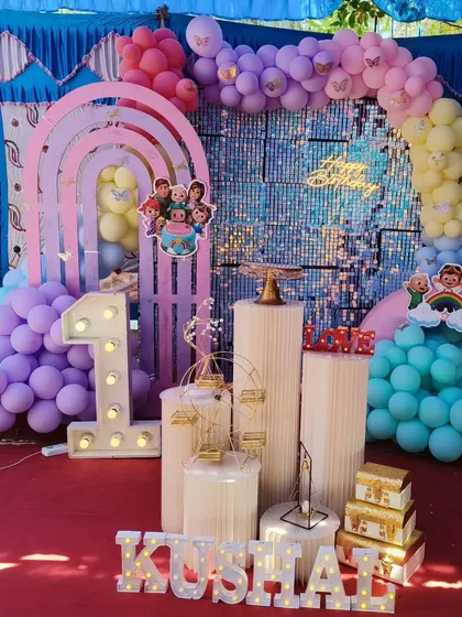 A playful and colorful first birthday party with a Cocomelon-inspired theme, using pastel rainbow balloons and a shimmering blue backdrop.