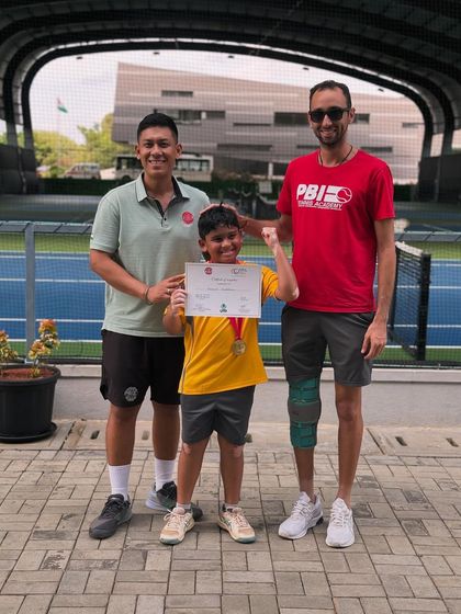 A young player celebrates his achievement with his coaches. We believe in recognizing every milestone in a player's development journey.