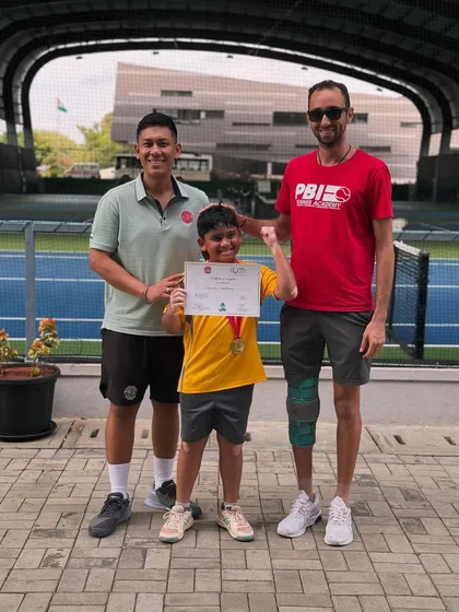 A young player celebrates his achievement with his coaches. We believe in recognizing every milestone in a player's development journey.