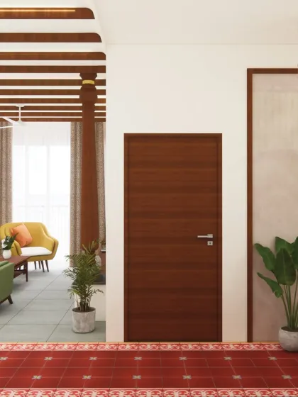 A clean, simple wooden door stands in contrast to the textured red Athangudi tile floor, creating a moment of minimalist calm. The design balances intricate traditional details with modern simplicity.