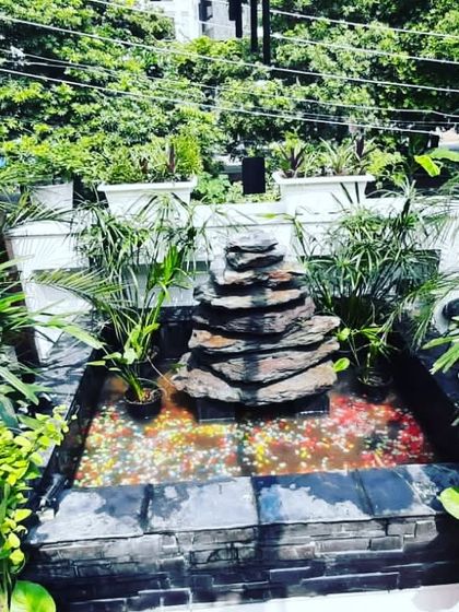 A custom-built water feature with a stacked slate design, nestled among lush greenery in a beautiful balcony garden.