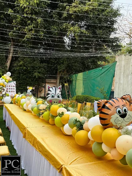 A closer look at the playful table runner for the kids' seating area. Large foil balloons shaped like a tiger and zebra pop out from the arrangement, adding a delightful touch to the safari birthday party decor.