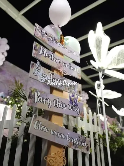 Lighting and signage help guide guests and add to the atmosphere. These glowing butterfly lamps and a custom directional signpost were perfect for this nighttime fairy party.