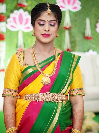 A beautiful close-up of Preethi at her baby shower. The makeup features bright, festive colors to match her multi-colored saree.