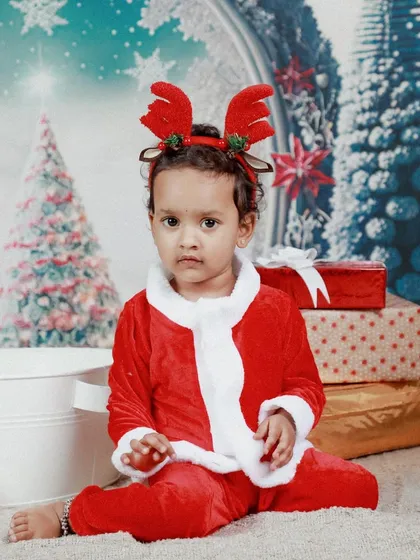 A cute little reindeer! Themed Christmas shoots are so much fun, and this toddler looks adorable in his Santa suit and reindeer antlers.