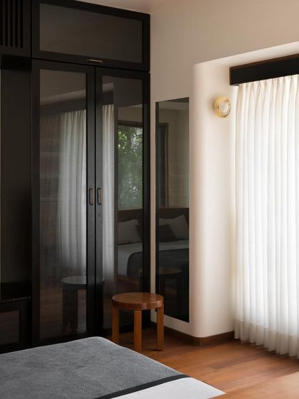 A bedroom featuring a custom wardrobe with smoked glass doors. This choice of material adds a sleek, modern touch and reflects the light in the room, making the space feel larger.