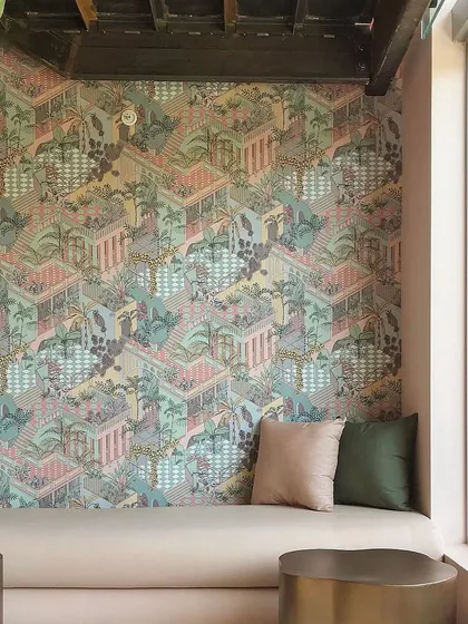 In this relaxed seating area, the 'Miami' wallpaper provides a vibrant, layered backdrop. The giddy tiers of terraces and rich foliage create a playful yet sophisticated atmosphere.
