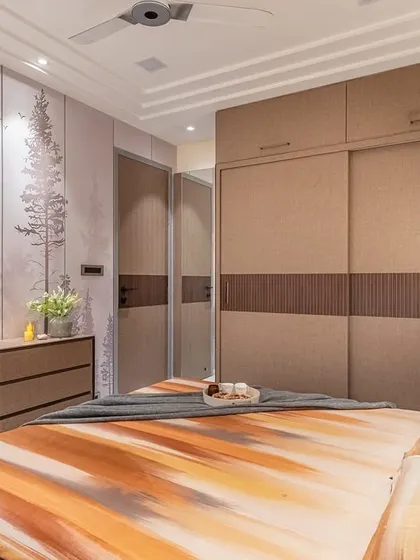 This angle shows the seamless integration of the wardrobe and the nature-themed accent wall. The wardrobe features a mix of textured laminate and a dark wood-grain band, tying together all the earthy elements used throughout the room.