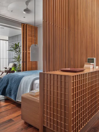 A closer look at the master bedroom's custom wooden screen, which combines solid and latticed sections. This detail adds texture and a sense of lightness, while partially screening the sleeping area from the dressing space.
