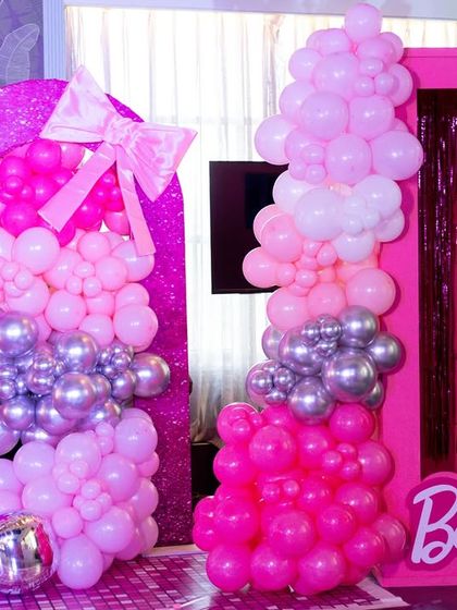A close-up of the Barbie party decor, showing the pink and silver balloon columns and the entrance to the "Barbie box" photo booth.