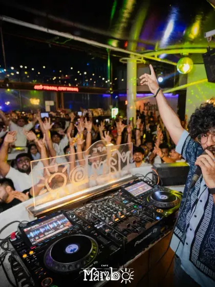 Connecting with the crowd is key to a great party. Here I am on the mic at Cafe Mambo, getting everyone's hands in the air for a massive moment. I know how to read the room and keep the energy at its peak all night long.