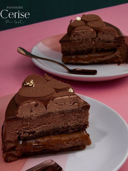 Two slices of Midnight Sun, revealing the deep layers of chocolate mousse and rich caramel. It is a moment of pure, balanced indulgence.