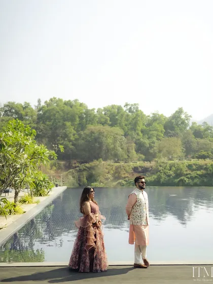 A stylish portrait of the couple by the water. The wide shot captures the beautiful scenery of the venue, making it a perfect destination wedding photograph.