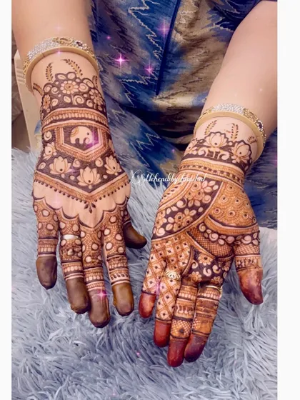 A lovely Teej festival design with a mix of styles. One hand has a traditional elephant and lotus pattern, while the other features a modern floral design.