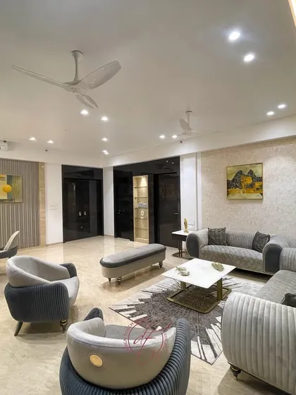 A wide shot of a living and dining area defined by a cool, calming palette of blues and whites. The design features a plush grey sofa, an abstract rug, and a cohesive seating arrangement that feels both spacious and intimate.