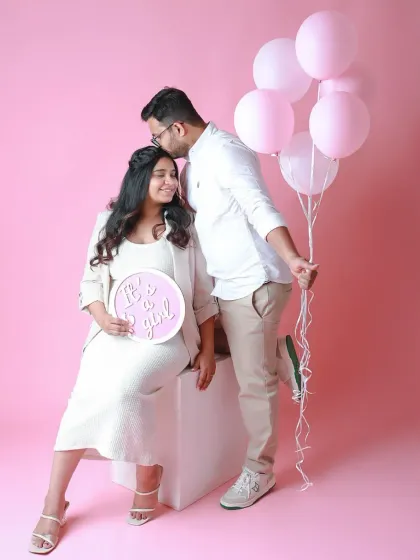 A sweet gender reveal for a baby girl. The pink balloons and "It's a girl" sign make for a beautiful and celebratory couple's portrait.
