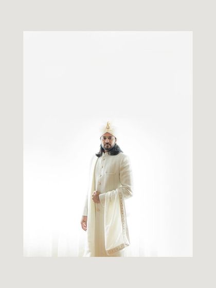 A minimalist and striking portrait of the groom in his white wedding attire. The high-key lighting creates a modern and ethereal look.