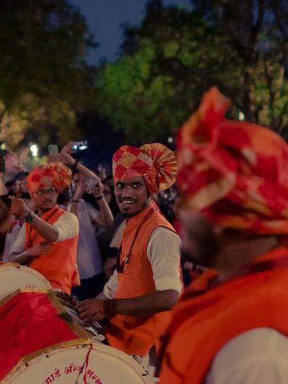 A dhol player in a bright orange turban looks directly at the camera and smiles while performing. Even in a crowd, I look for these moments of direct connection.