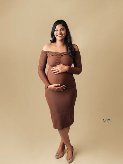 A smiling portrait of a mom-to-be in a simple brown dress, taken in my studio.
