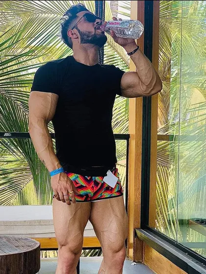 Hydration is key for performance and muscle fullness. Taking a water break during an outdoor shoot, showcasing a lean and vascular physique.