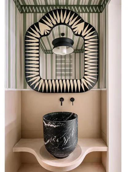 The powder room in Eden House is a jewel box of a space. A bold, graphic mirror from Scarlet Splendour and a black marble sink create a dramatic and elegant statement.