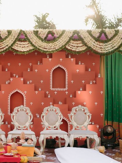 The stage is set for the Maharashtrian Haldi ceremony. The combination of the unique backdrop, elegant white chairs, and traditional floral garlands created a space that was both grand and deeply personal.