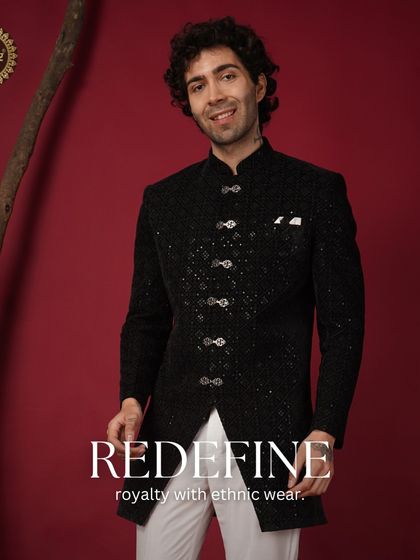 Redefine royalty with ethnic wear. A model in a black sequined Indo-Western sherwani, paired with white trousers for a striking look.