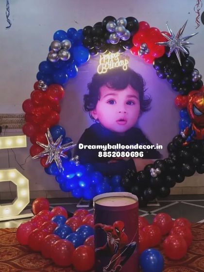 A personalized Spiderman theme for a 5th birthday. This setup features a custom backdrop with the child's photo, a balloon ring in Spiderman colors, and a light-up marquee number '5'.