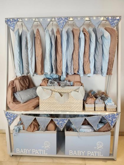 A custom-built wardrobe setup for Baby Patil, displaying a collection of beautifully packaged baby clothes and essentials in soft, serene colors.