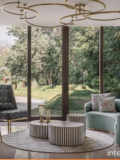 In this jewel box living space at The Aangan, floor-to-ceiling windows frame the lush garden views, blurring the line between indoors and outdoors. The circular motif in the lighting and rug adds a soft, harmonious flow to the room.