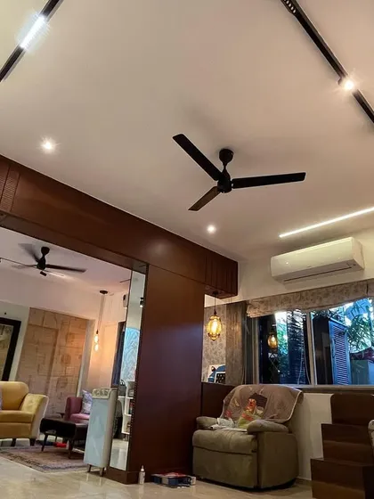 A wide view of an open-plan living space, showing how different lighting elements like track lights, recessed LEDs, and ceiling fans are integrated to define different zones.