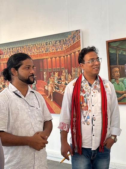 Chatting with fellow artists and visitors at my exhibition in front of a large, satirical painting.