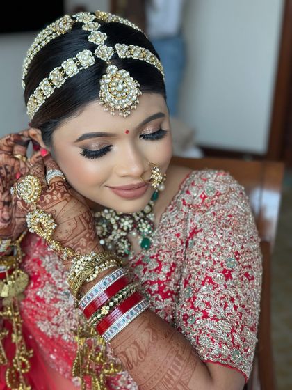 A close-up of the bride getting ready, showing the intricate details of her jewelry and her sleek bridal bun.