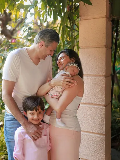 Such a heartwarming exchange. This candid outdoor shot captures the laughter and love of a family of four, completely smitten with their new arrival.