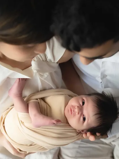 A precious moment of connection as a newborn, held by their parents, looks up with wide-eyed wonder. It's a beautiful glimpse into their developing personality.