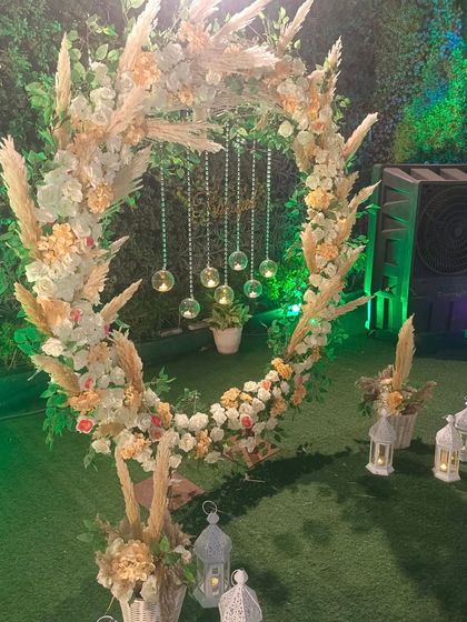 A rustic yet elegant photo booth for an outdoor party. This circular wreath is made with pampas grass and pastel flowers, with hanging crystal globes for a magical touch.