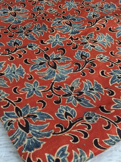 A close-up of a beautiful Ajrakh print on modal fabric. The intricate floral design in blue and black on a red base is simply timeless.