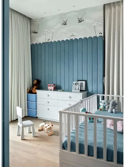 A full view of Rockstar Remy's nursery. The room features midnight blue padded walls that are nano-coated for safety, a soft wooden floor, and a custom cot. The pandas on hot air balloons wallpaper adds a touch of whimsy.