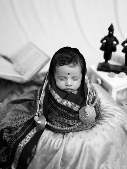 A close-up monochrome portrait of the baby as 'Rakhumai', emphasizing the peacefulness and innocence of the moment.