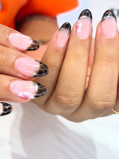 A modern take on a dark French manicure. This design features a sheer black tip with a subtle floral detail, creating a look that is both edgy and delicate.