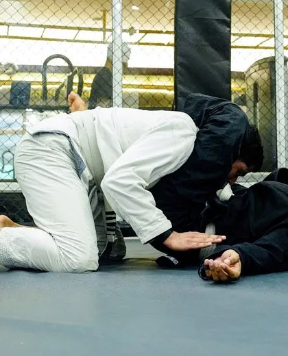 A student in a white Gi works to secure a pin on their opponent. Mastering positional control is the first step to setting up submissions.