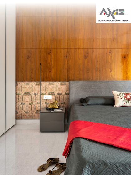 This bedroom design blends modern lines with traditional motifs. The clean, wood-paneled wall is complemented by a wallpaper accent featuring a classic Indian-inspired pattern, adding a unique and personal touch.