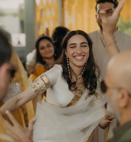 A bride's joy is infectious. This is a favorite shot from a Haldi ceremony, where the bride is radiant in a custom-styled white and gold ensemble. It’s a look we designed to be as free-spirited and happy as she is.